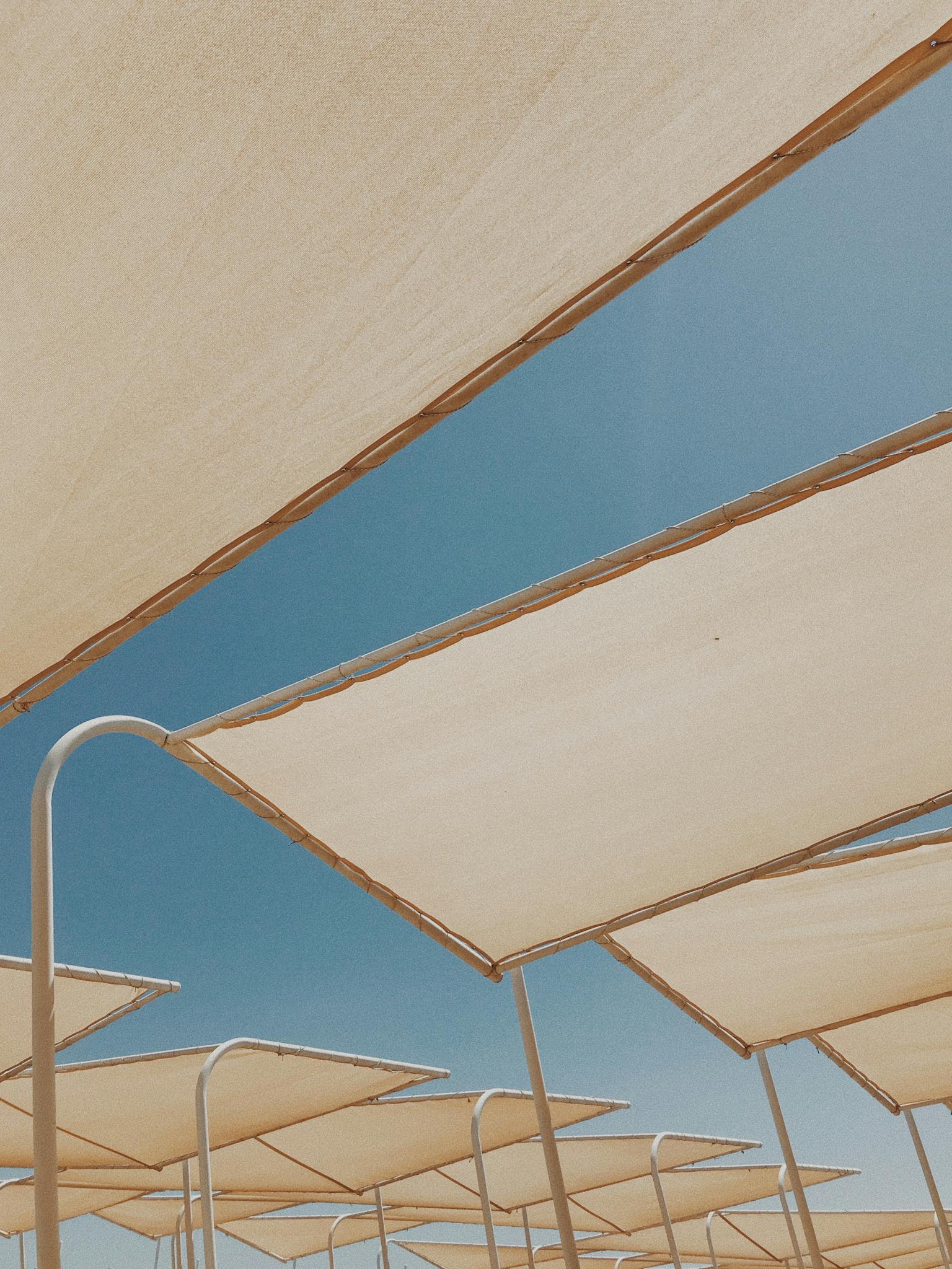 Low angle view of modern sun shades under a clear blue sky, perfect for summer concepts.