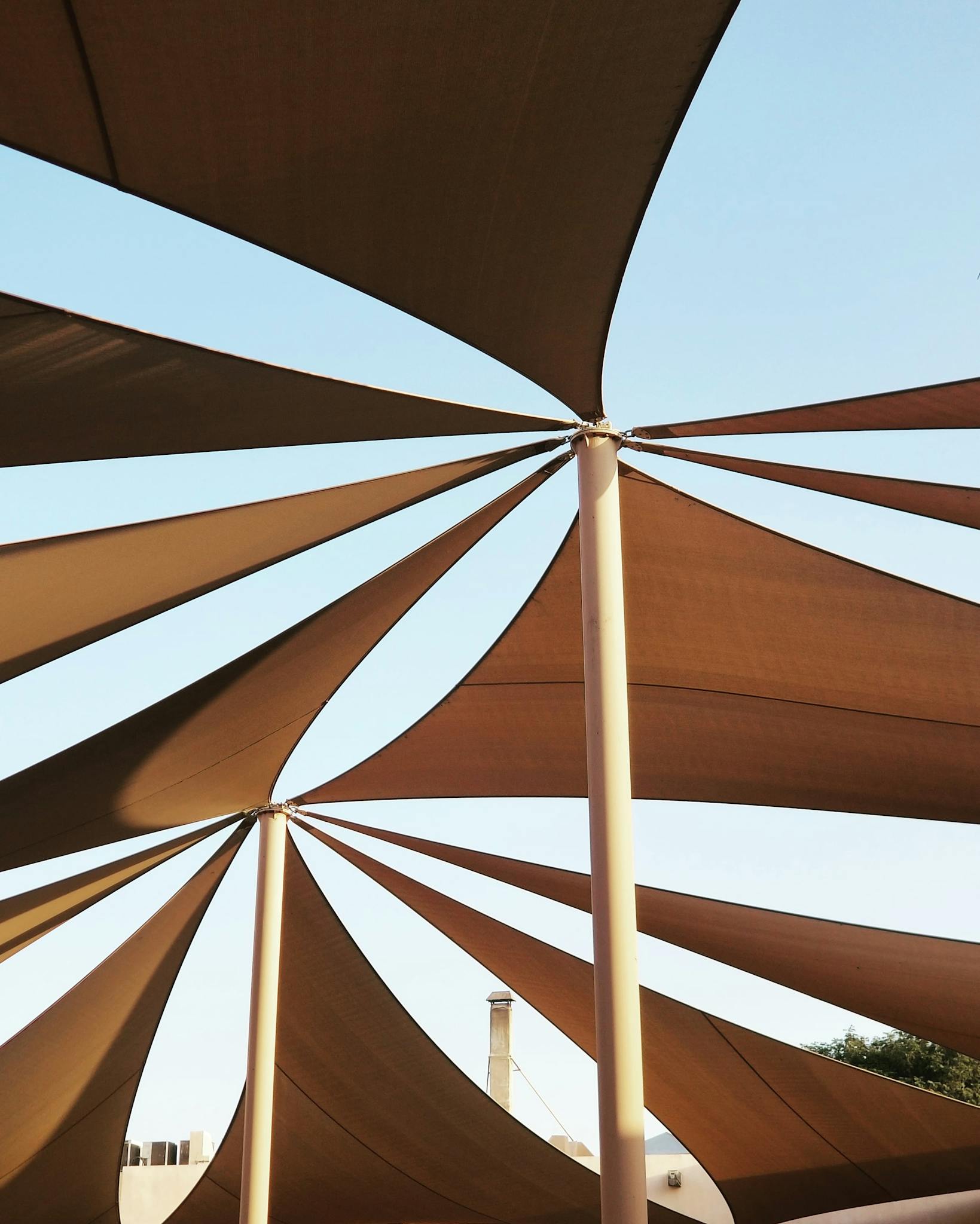 Modern architectural shade structures against a clear blue sky in Qatar.