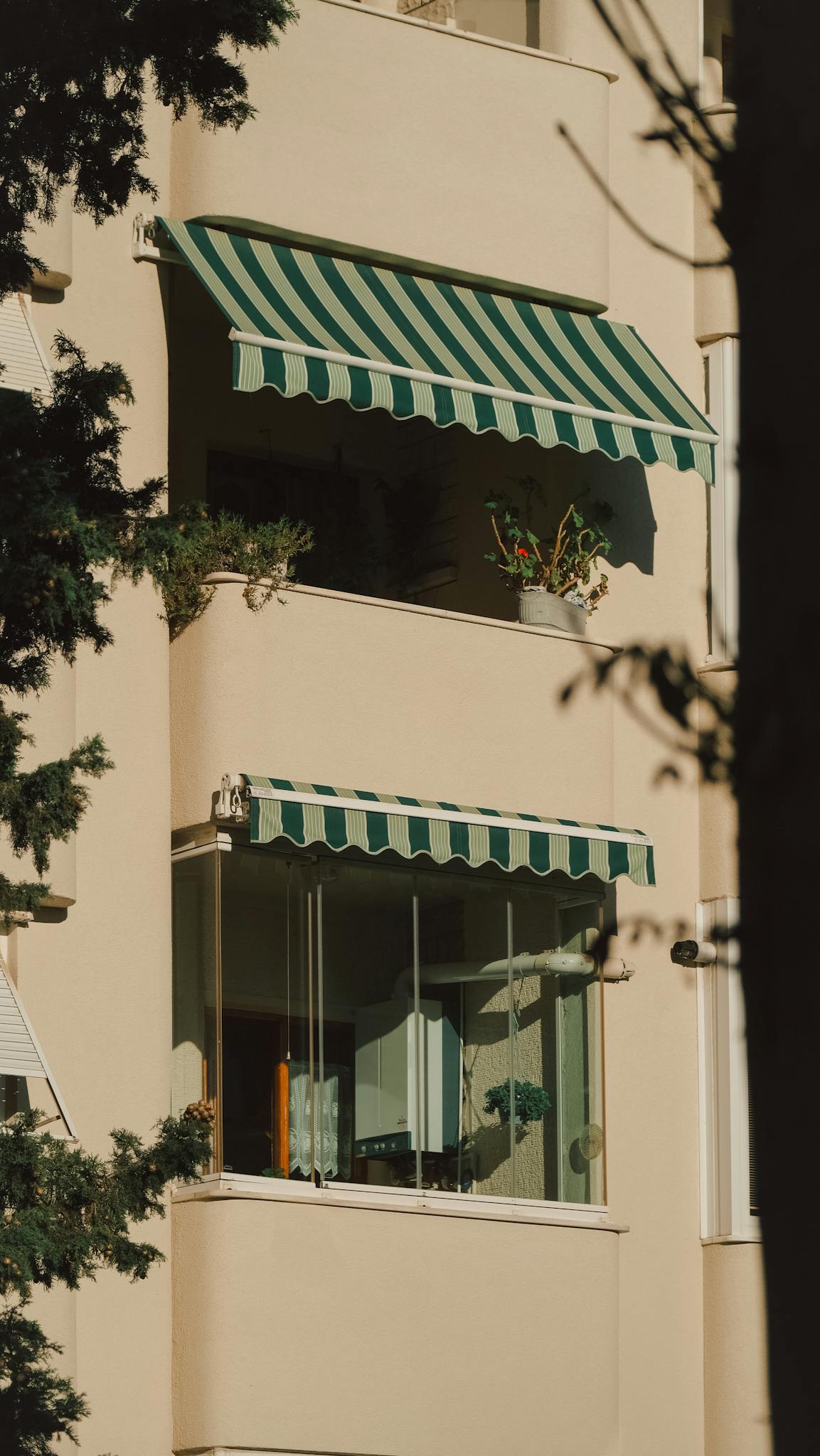View of a city apartment's facade with green-striped awnings and balconies.